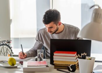 A person writing on a book Description automatically generated with low confidence