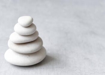 Stack of white pebbles on a neutral light grey background as balance and wellness concept Stack of white pebbles on a neutral light grey background as balance and wellness concept mindfulness stock pictures, royalty-free photos & images